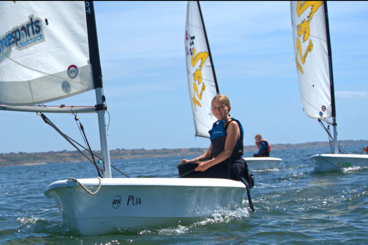 People sailing small boats on a sunny day with clear skies.
