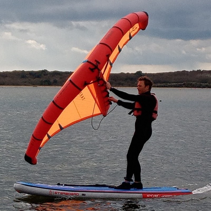 a man flying a kite in a large body of water